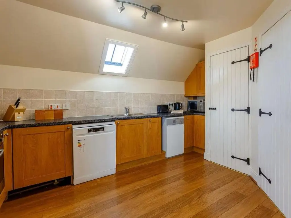 a large kitchen with wooden cabinets and a window at Craiglea Barn in Latheron