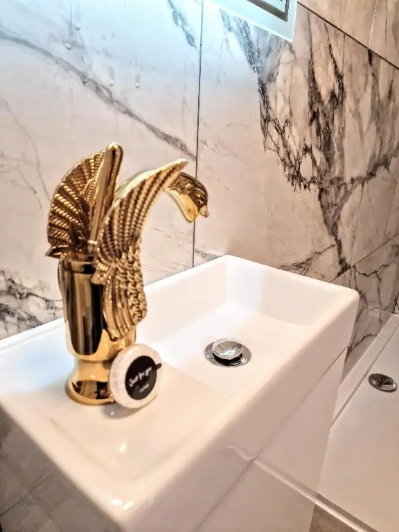 a bathroom with a gold faucet on a sink at Kaoglen Lodge - Fawn Pod - Hot Tub - Dogs - Pitlochry - Luxury in Blairgowrie