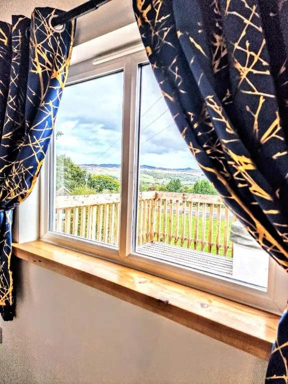 a window with a view of a deck at Kaoglen Lodge - Fawn Pod - Hot Tub - Dogs - Pitlochry - Luxury in Blairgowrie