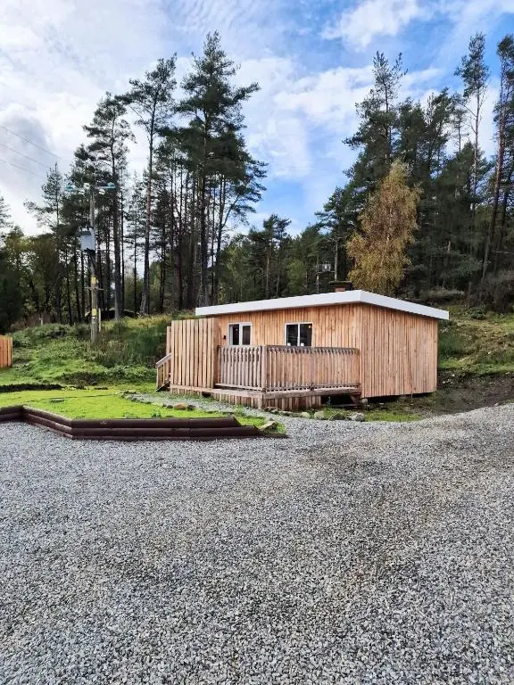 a small wooden building on the side of a road at Kaoglen Lodge - Fawn Pod - Hot Tub - Dogs - Pitlochry - Luxury in Blairgowrie