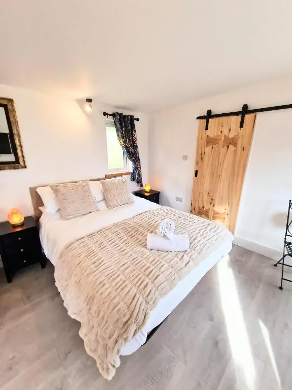 a bedroom with a large bed with a wooden door at Kaoglen Lodge - Fawn Pod - Hot Tub - Dogs - Pitlochry - Luxury in Blairgowrie