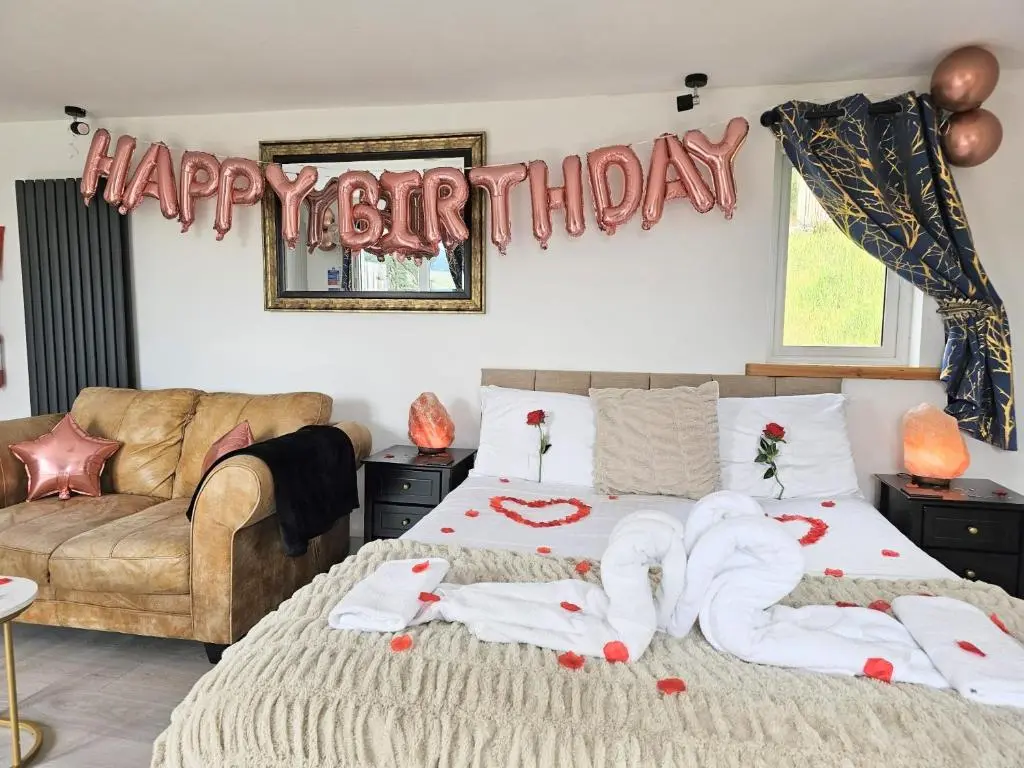 a bedroom with a bed with a happy birthday sign at Kaoglen Lodge - Fawn Pod - Hot Tub - Dogs - Pitlochry - Luxury in Blairgowrie