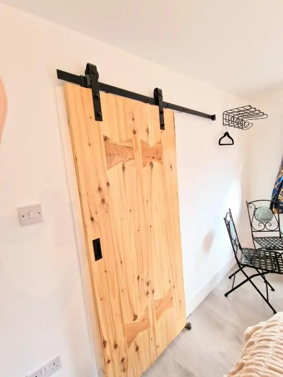a sliding door in a room with a chair at Kaoglen Buck Pod - Hot Tub - Dog Friendly in Blairgowrie