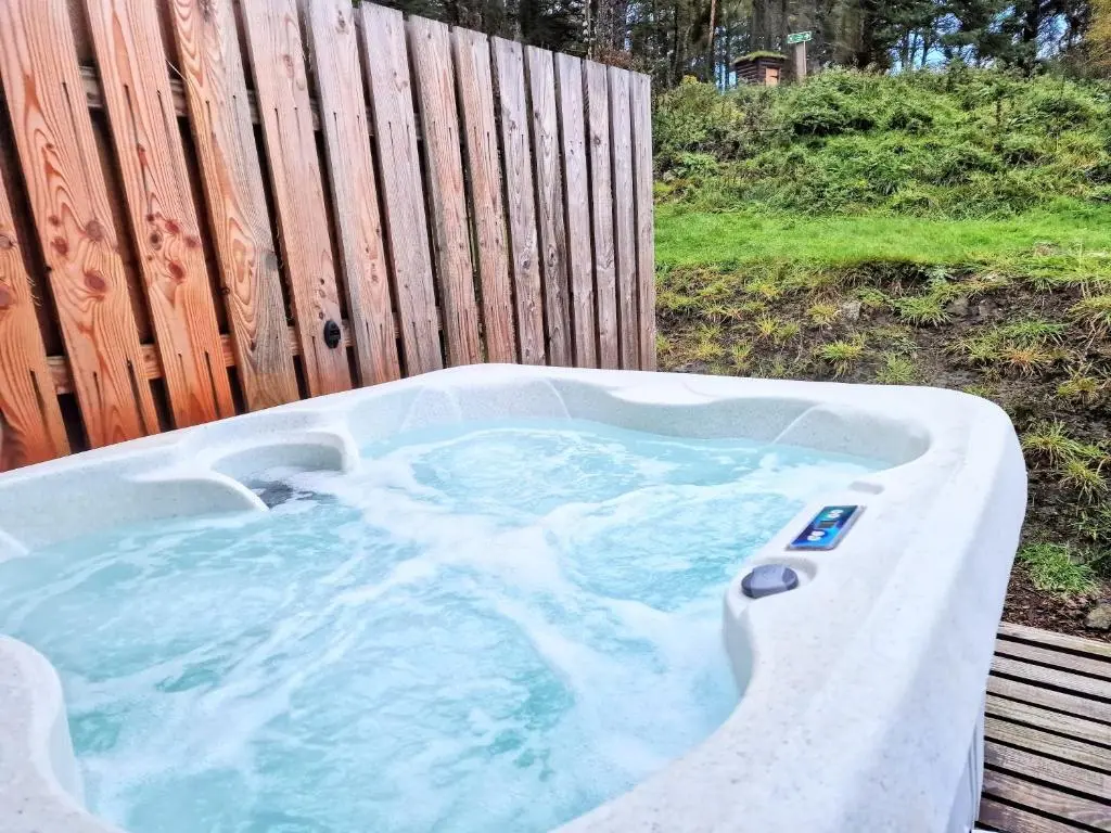 a hot tub sitting next to a wooden fence at Kaoglen Buck Pod - Hot Tub - Dog Friendly in Blairgowrie