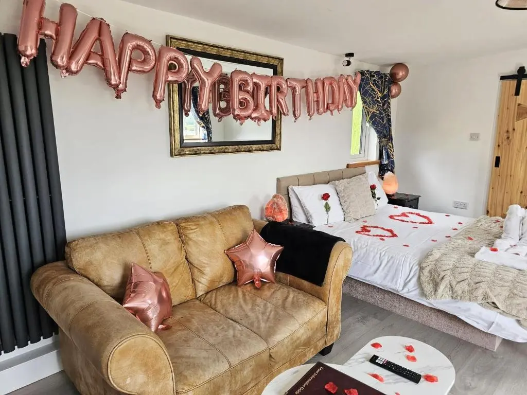 a living room with a couch and a happy birthday sign at Kaoglen Fallow Pod - Luxury - Hot Tub - Pet Friendly in Blairgowrie