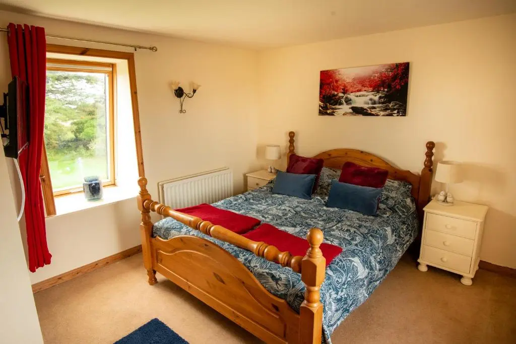 a bedroom with a wooden bed with blue and red pillows at The High Croft in Rogart