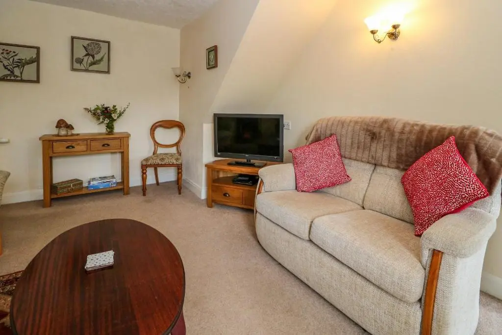 a living room with a couch and a tv at Rose Cottage in Strathpeffer