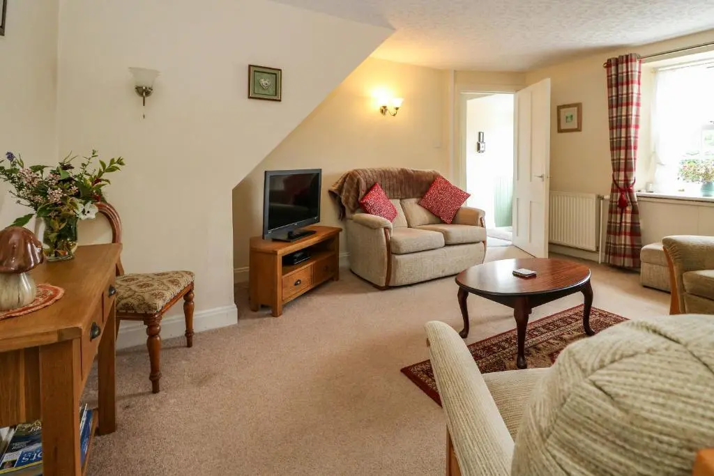 a living room with a couch and a tv at Rose Cottage in Strathpeffer
