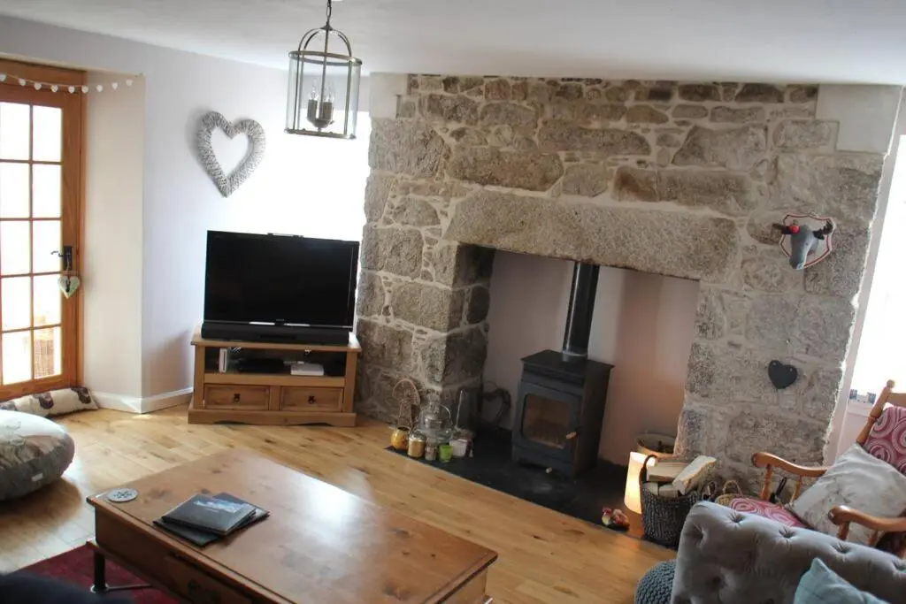a living room with a stone fireplace and a tv at Upper Corronich in Boat of Garten
