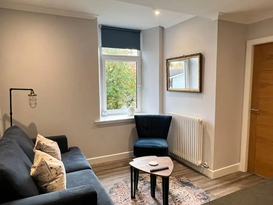 a living room with a blue couch and a chair at Kingsmills Apartment in Inverness