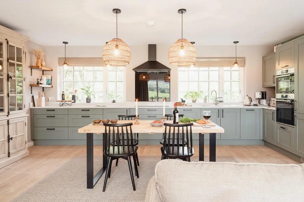 a kitchen with blue cabinets and a table with chairs at Culfoichbeg Lodge - Seasgair Lodges in Grantown on Spey