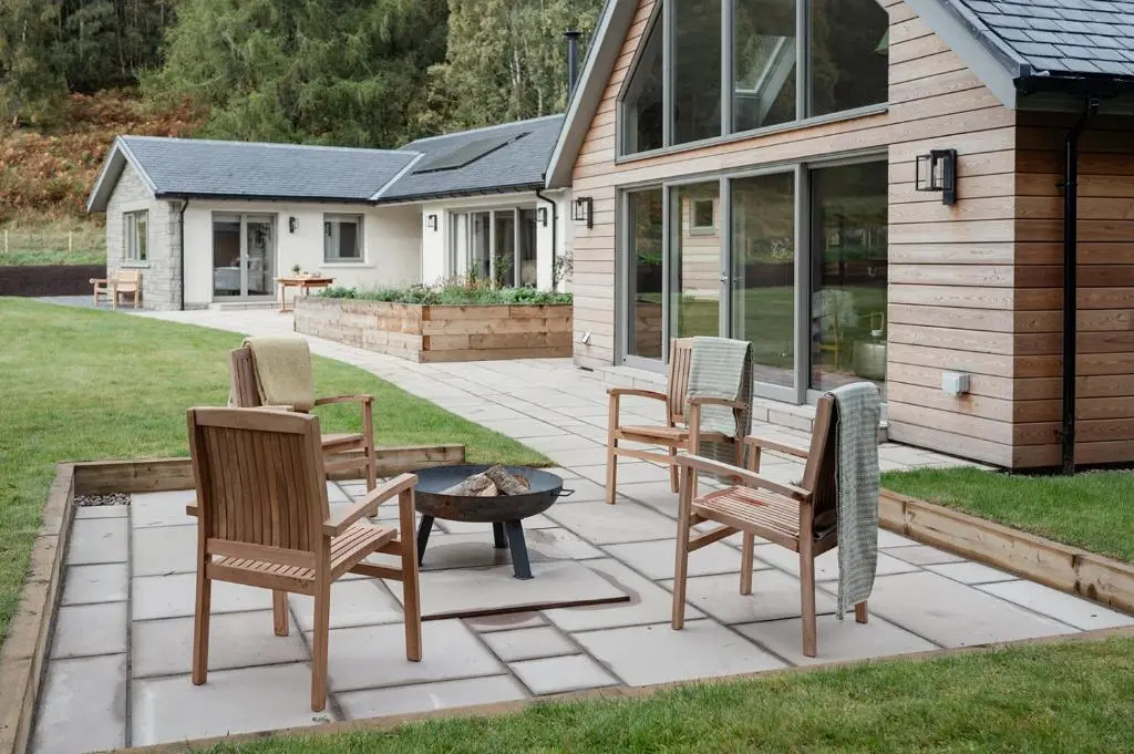 a patio with chairs and a fire pit in front of a house at Culfoichbeg Lodge - Seasgair Lodges in Grantown on Spey