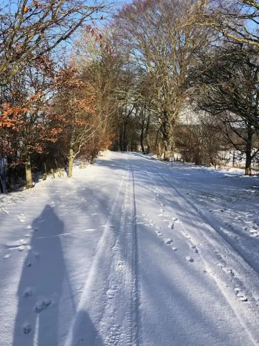a snow covered road with footprints in the snow at River Cottage in Turriff