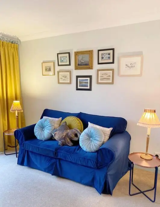 a dog laying on a blue couch with pillows at River Cottage in Turriff