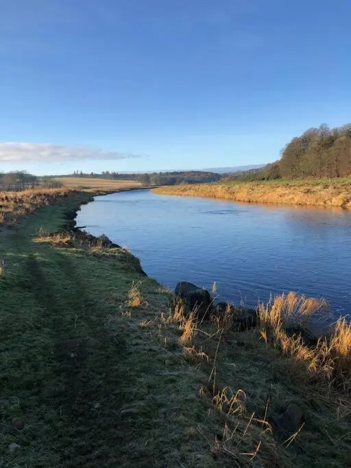 a body of water next to a grassy field at River Cottage in Turriff