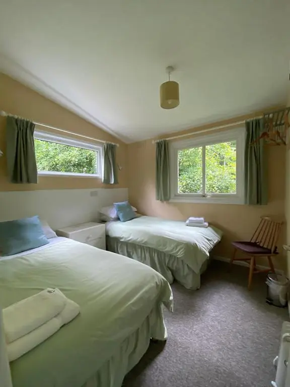 two beds in a room with two windows at Baillie Chalet on Reelig Estate in Kirkhill