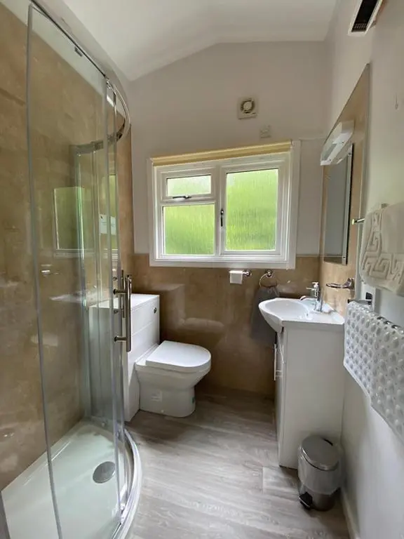 a bathroom with a shower and a toilet and a sink at Baillie Chalet on Reelig Estate in Kirkhill