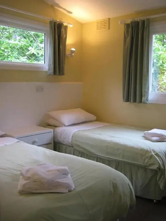 two beds in a room with two windows at Satchwell Chalet on Reelig Estate - Dog Friendly in Kirkhill