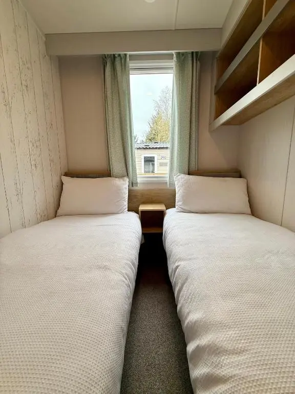 two beds in a small room with a window at The Ghillie's Van - Beautiful, luxury static caravan in Aberlour