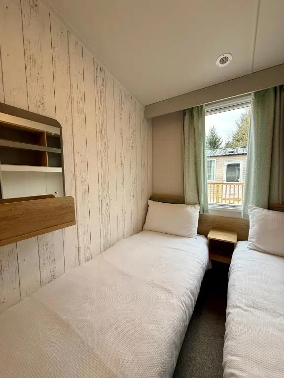two beds in a small room with a window at The Distiller\u2019s Van - Beautiful, luxury static caravan in Aberlour