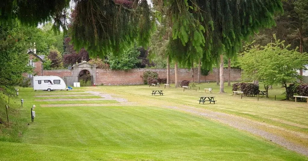 a park with benches and a trailer in the grass at The Distiller\u2019s Van - Beautiful, luxury static caravan in Aberlour