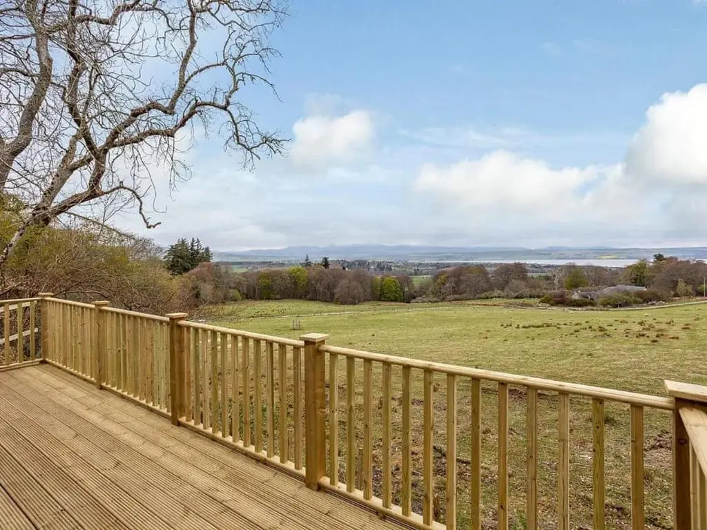 a wooden deck with a view of a field at Kilninver Chalet on Reelig Estate in Kirkhill