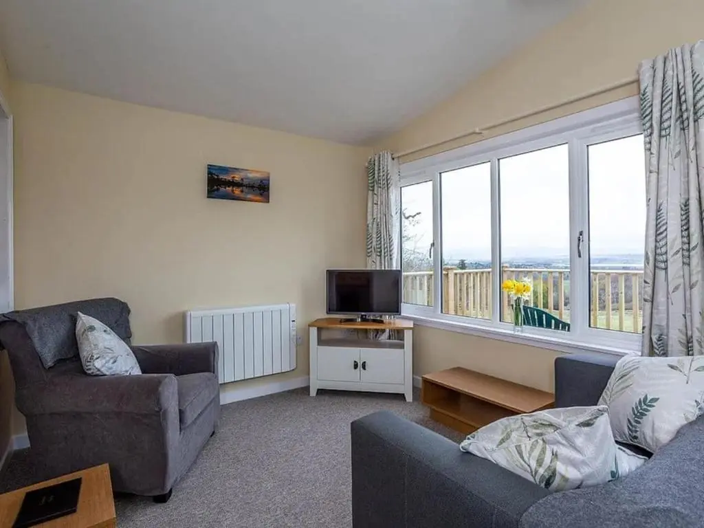 a living room with a couch and a tv at Kilninver Chalet on Reelig Estate in Kirkhill