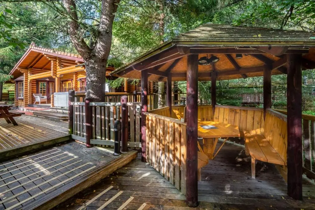 a wooden gazebo with a table and a bench at Beaver Creek Lodge in Aviemore
