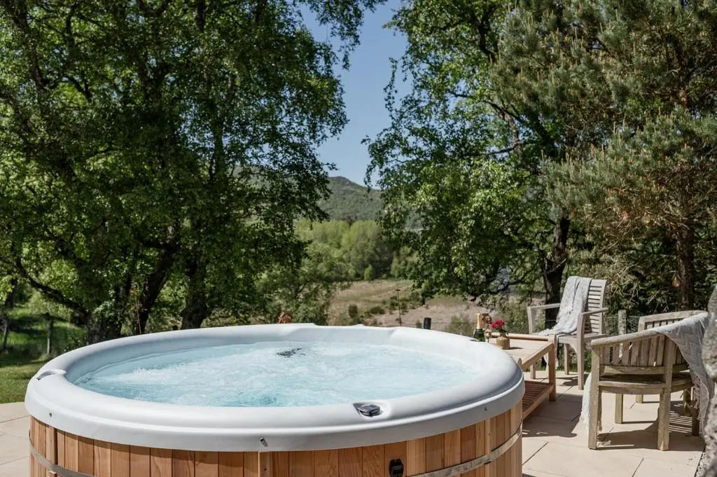 a hot tub on a patio with a table and chairs at Milton Lodge - Seasgair Lodges in Newtonmore