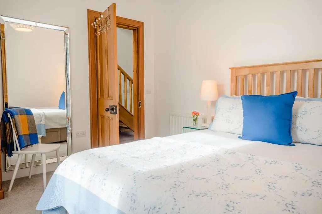 a bedroom with a blue and white bed and a mirror at Douglas Cottage - Seasgair Lodges in Boat of Garten