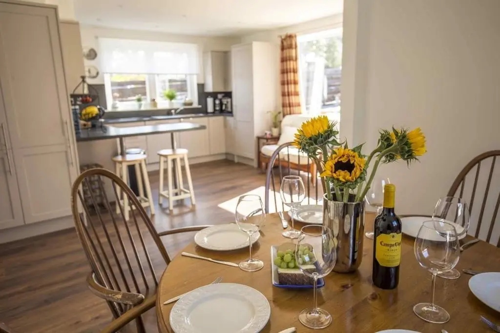 a dining room table with wine glasses and flowers on it at Douglas Cottage - Seasgair Lodges in Boat of Garten