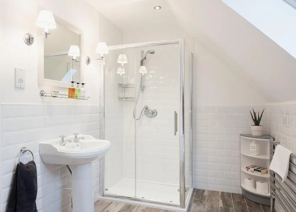 a white bathroom with a shower and a sink at Oak Cottage - Seasgair Lodges in Kincraig
