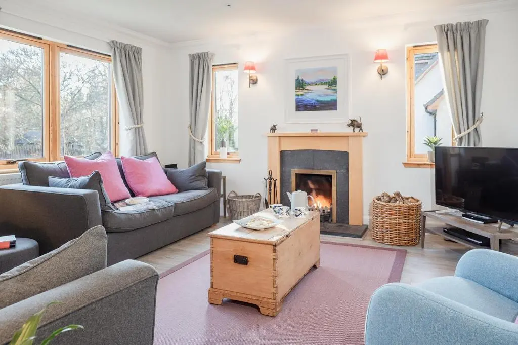 a living room with a couch and a fireplace at Oak Cottage - Seasgair Lodges in Kincraig