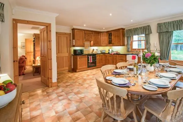 a kitchen with a table with chairs and a dining room at Rymore Wood Lodge - Seasgair Lodges in Nethy Bridge