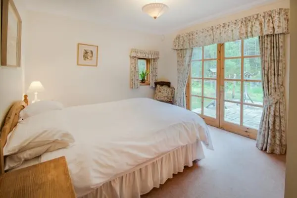 a bedroom with a large white bed and a window at Rymore Wood Lodge - Seasgair Lodges in Nethy Bridge