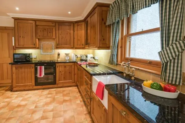 a kitchen with wooden cabinets and a bowl of fruit on the counter at Rymore Wood Lodge - Seasgair Lodges in Nethy Bridge