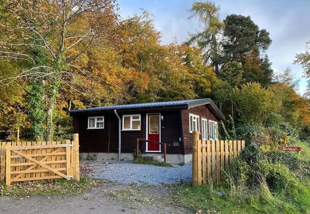 a small house with a wooden fence in front of it at Bridgend Chalet on Reelig Estate in Kirkhill