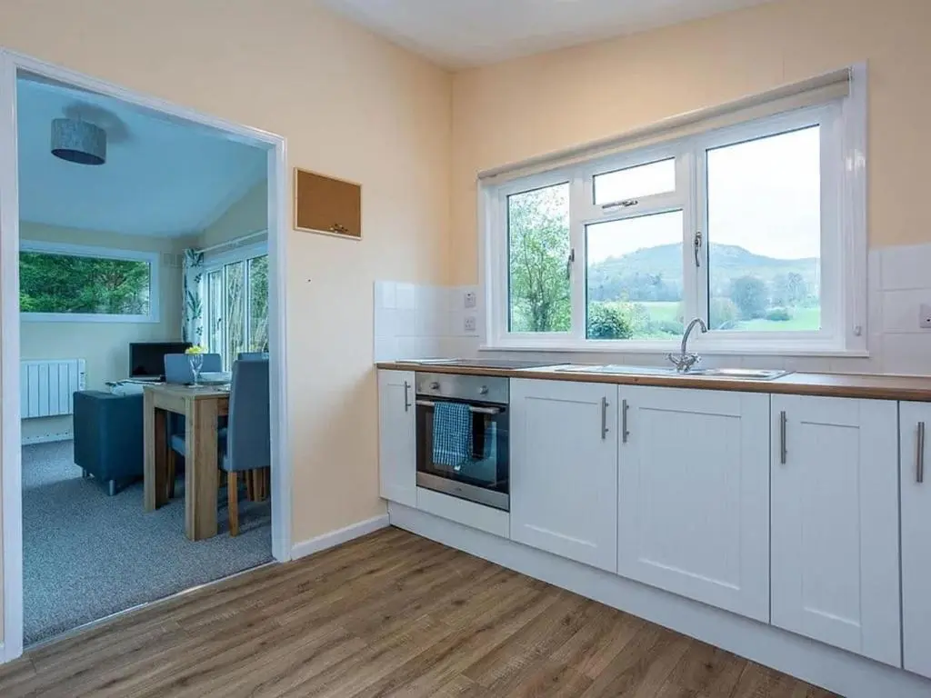 a kitchen with white cabinets and a sink and a table at Bridgend Chalet on Reelig Estate in Kirkhill