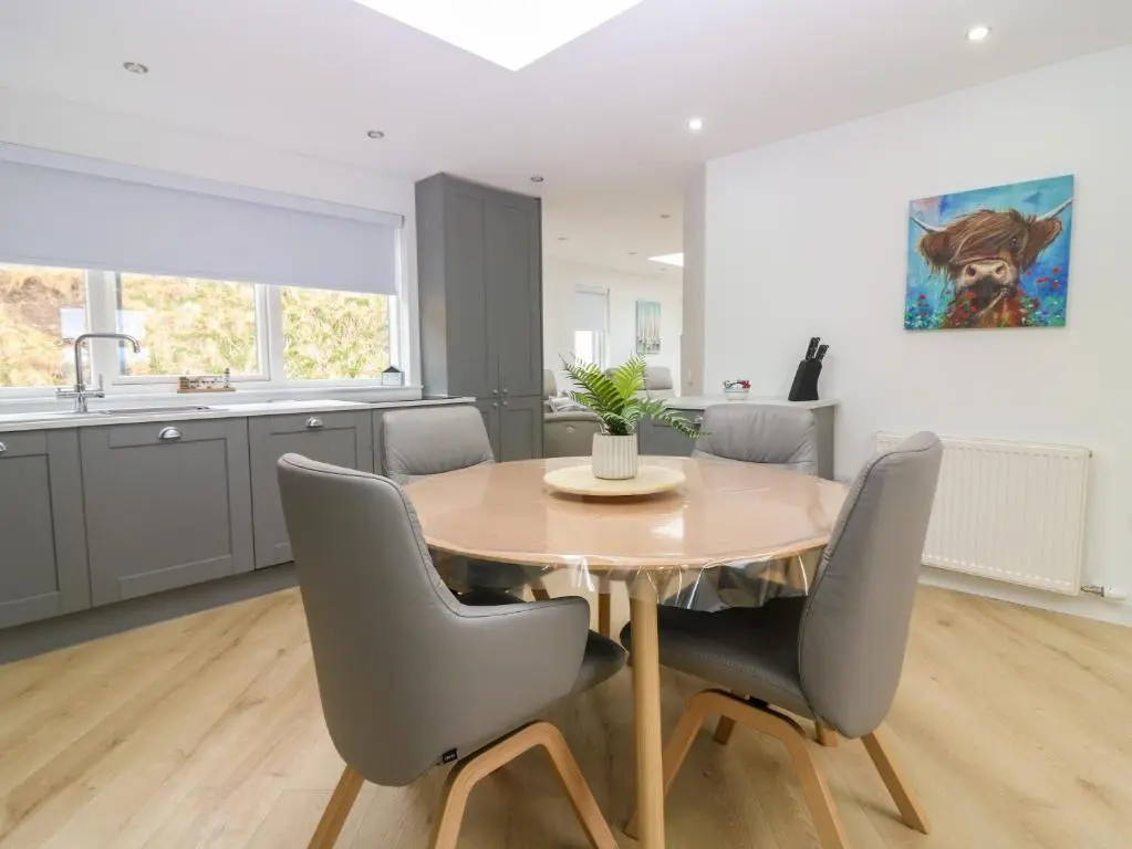 a kitchen and dining room with a wooden table and chairs at Craignure in Banff