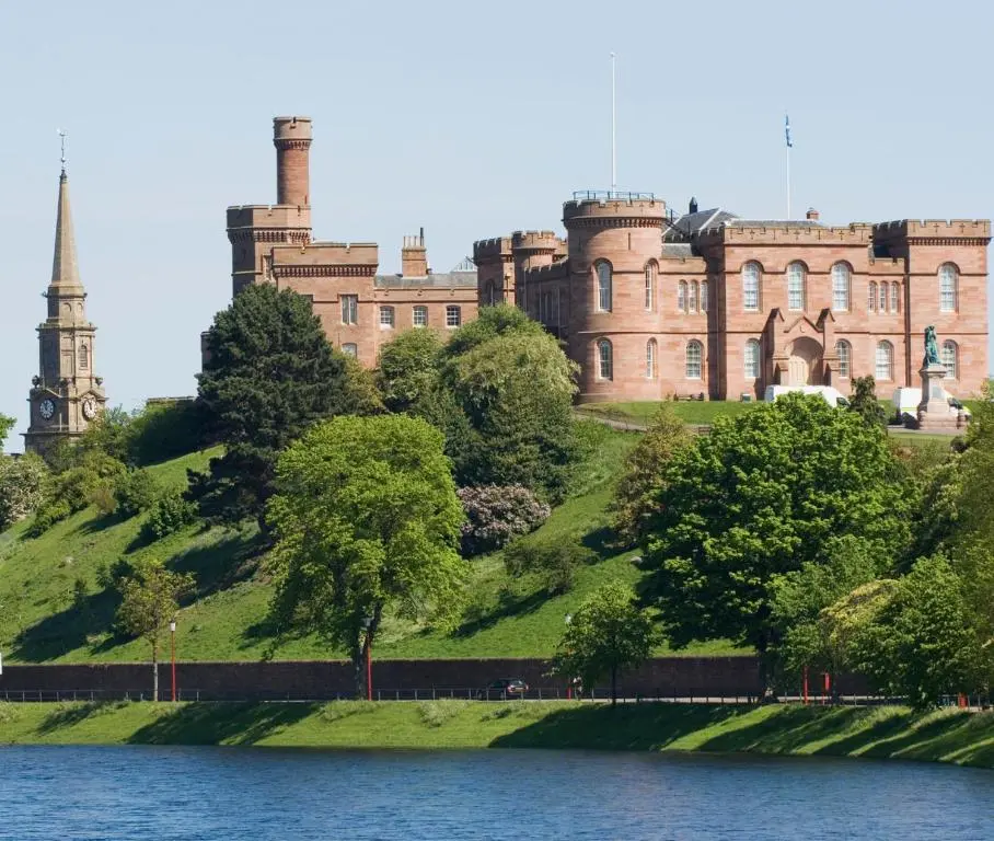 a large castle on a hill next to a body of water at Comfortable, modern apartment with parking. Inverness. in Inverness