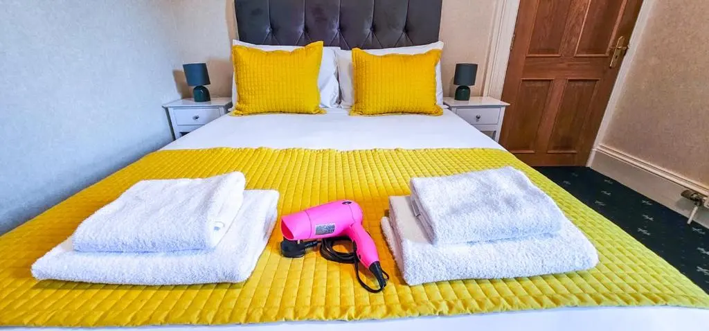 a bed with towels and a pink camera on it at mySTAYINN Abermar 12 Bedroom House in Inverness