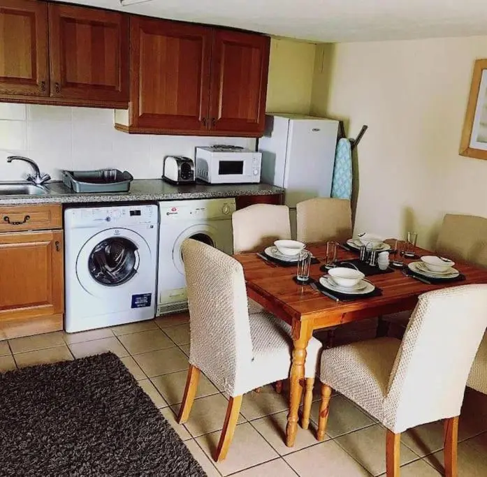 a kitchen with a wooden table with chairs and a microwave at Traditional Croft Cottage Minutes from Lochness in Drumnadrochit