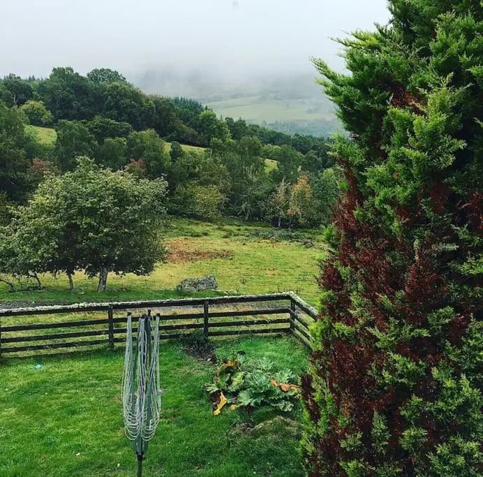 a metal object in a field next to a fence at Traditional Croft Cottage Minutes from Lochness in Drumnadrochit