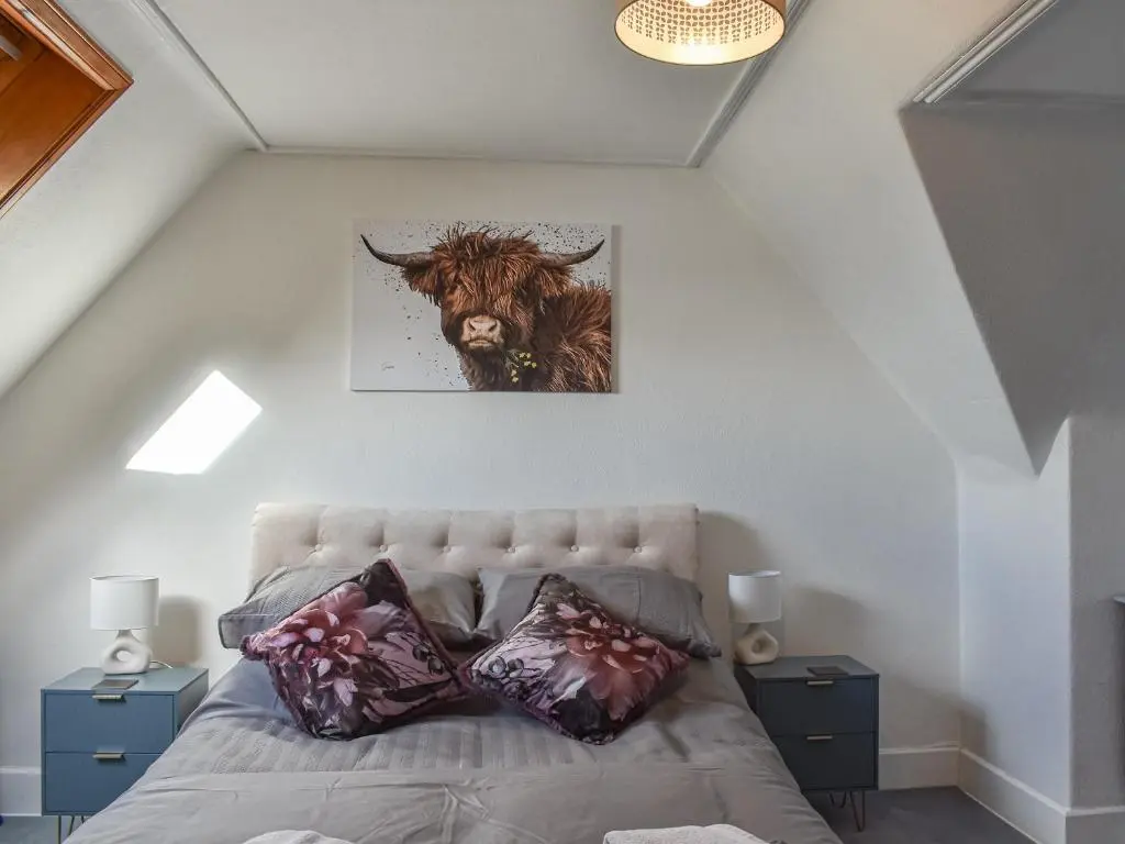 a bedroom with a bed with a cow on the wall at Strathlene Lodge in Ianstown