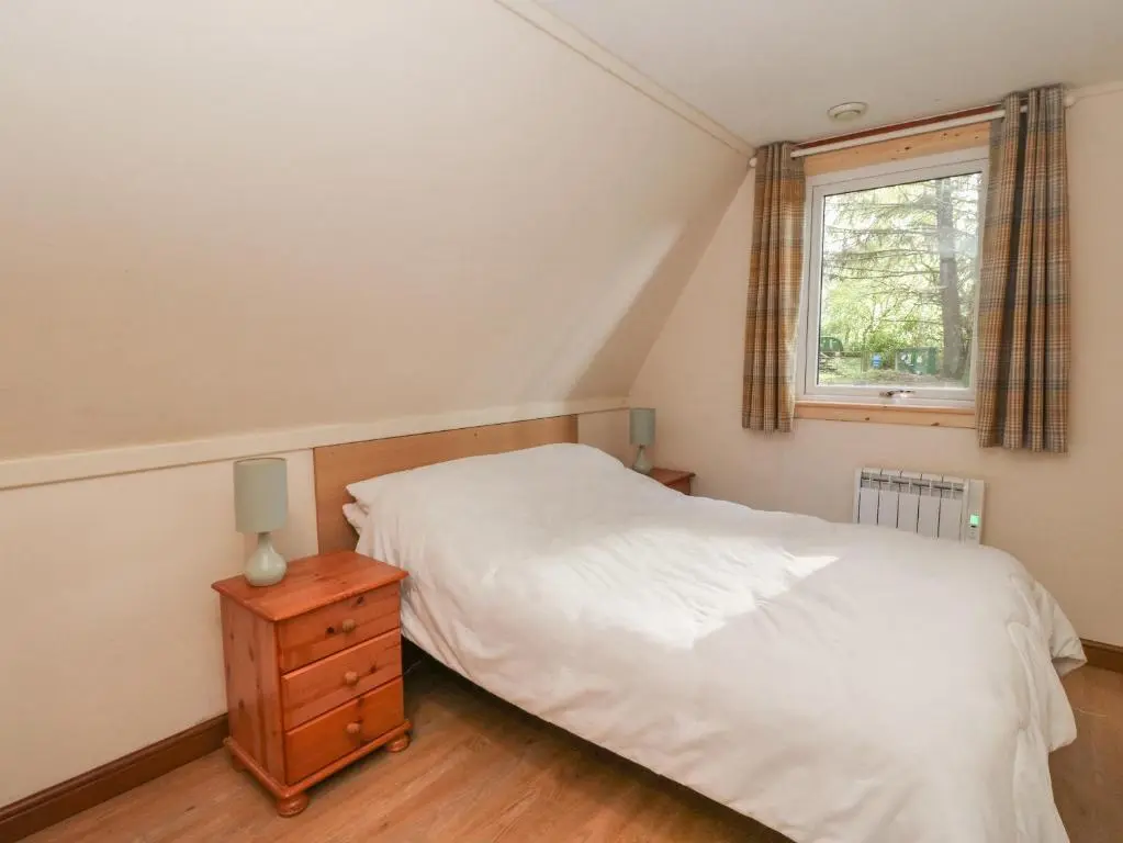 a bedroom with a white bed and a window at 27 Invergarry Lodges in Spean Bridge