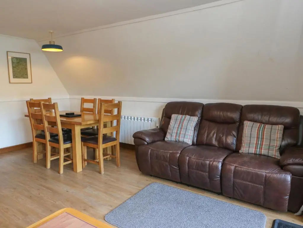 a living room with a leather couch and a table at 27 Invergarry Lodges in Spean Bridge