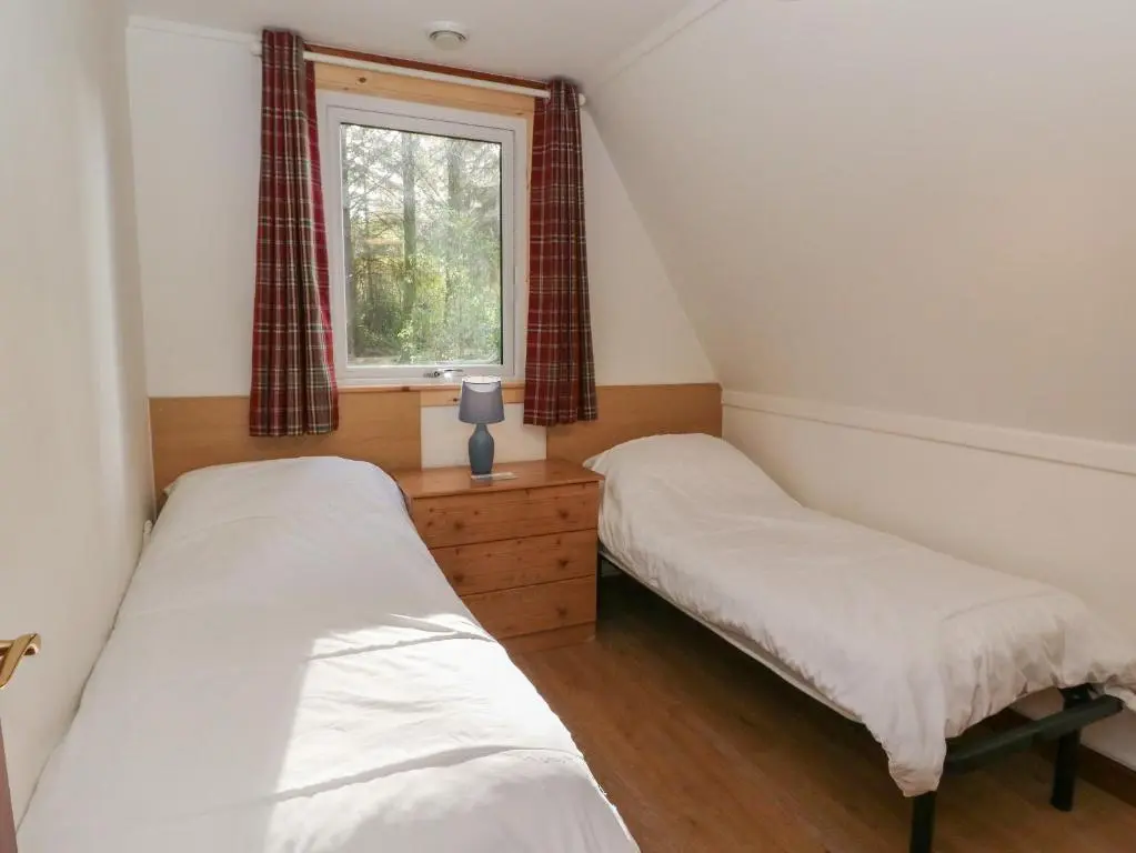 two beds in a small room with a window at 27 Invergarry Lodges in Spean Bridge