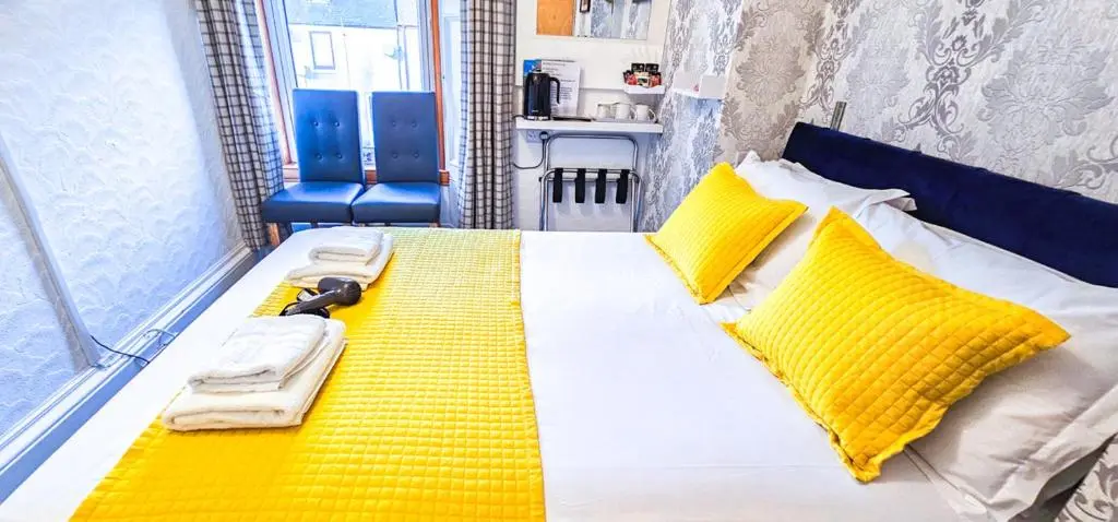 a bedroom with a bed with yellow and white sheets and yellow pillows at mySTAYINN Kinloch 7 Bedroom House in Inverness