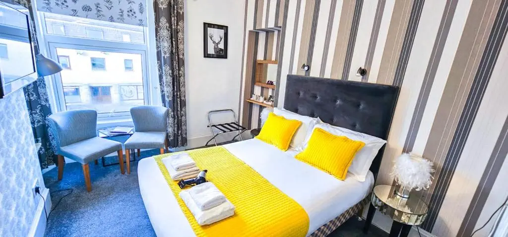 a bedroom with a large bed with yellow pillows at mySTAYINN Kinloch 7 Bedroom House in Inverness