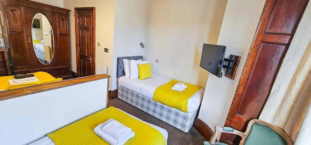 a small room with two beds and a mirror at mySTAYINN Melrose Villa in Inverness